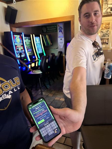 A guest handing his phone to staff to confirm a reward with the staff PIN